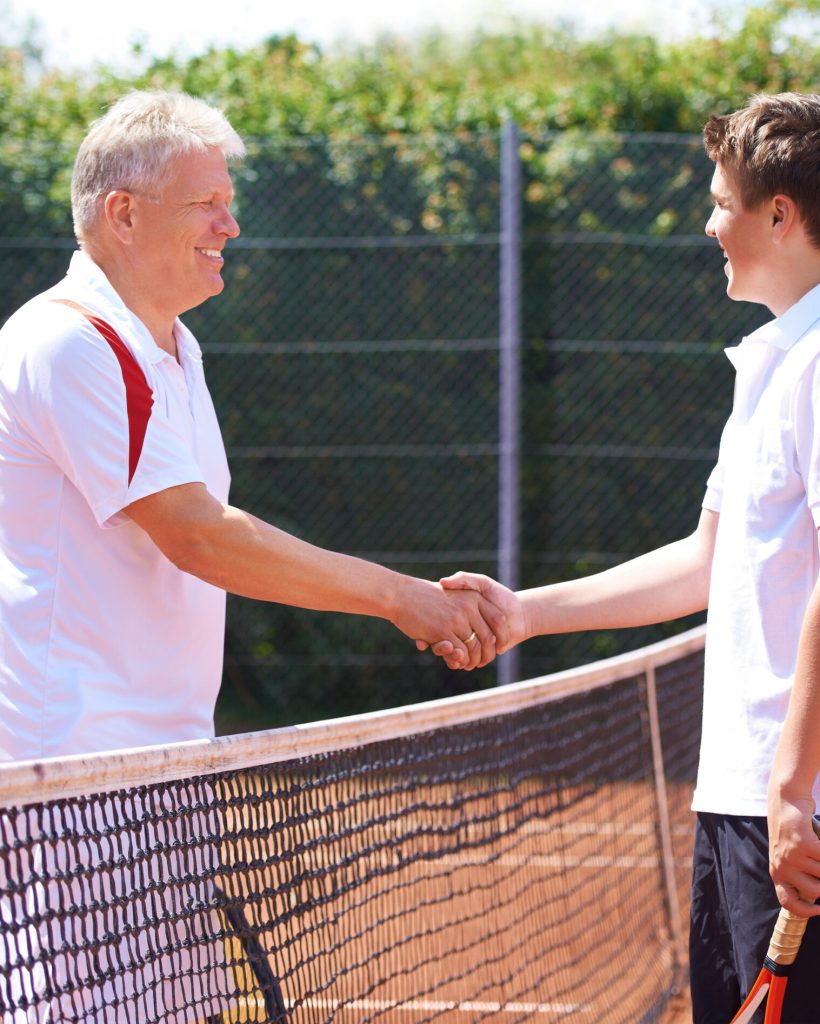 Good game son. A father and son shaking hands after a friendly game of tennis