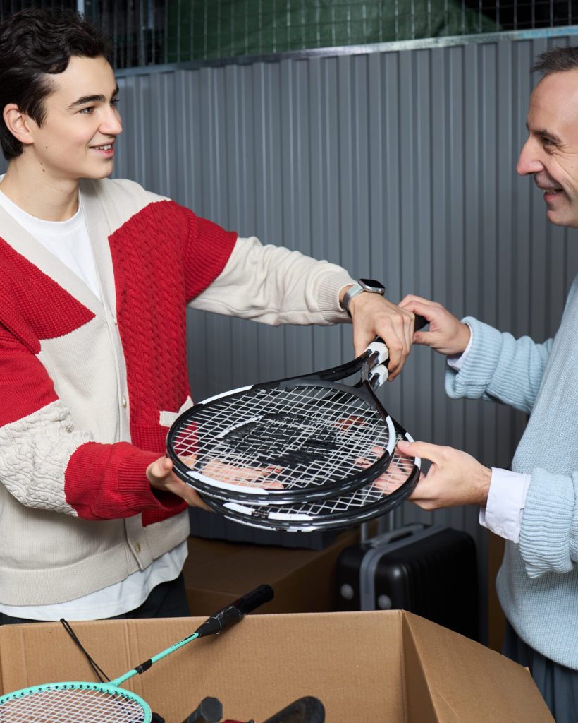 two-men-exchange-tennis-rackets-in-storage-unit-2026-03-05-11-38-17-utc
